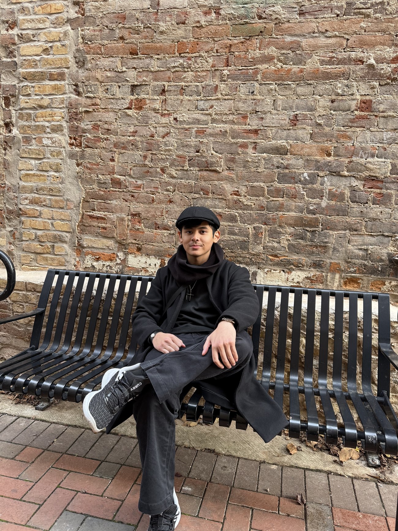 Dre, sitting on a bench against a brick wall